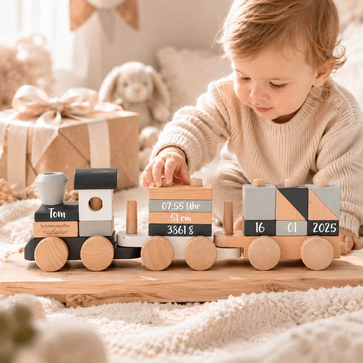 Baby spielt mit personalisiertem Holzzug zur Geburt mit Name, Geburtsdatum, Uhrzeit, Größe und Gewicht